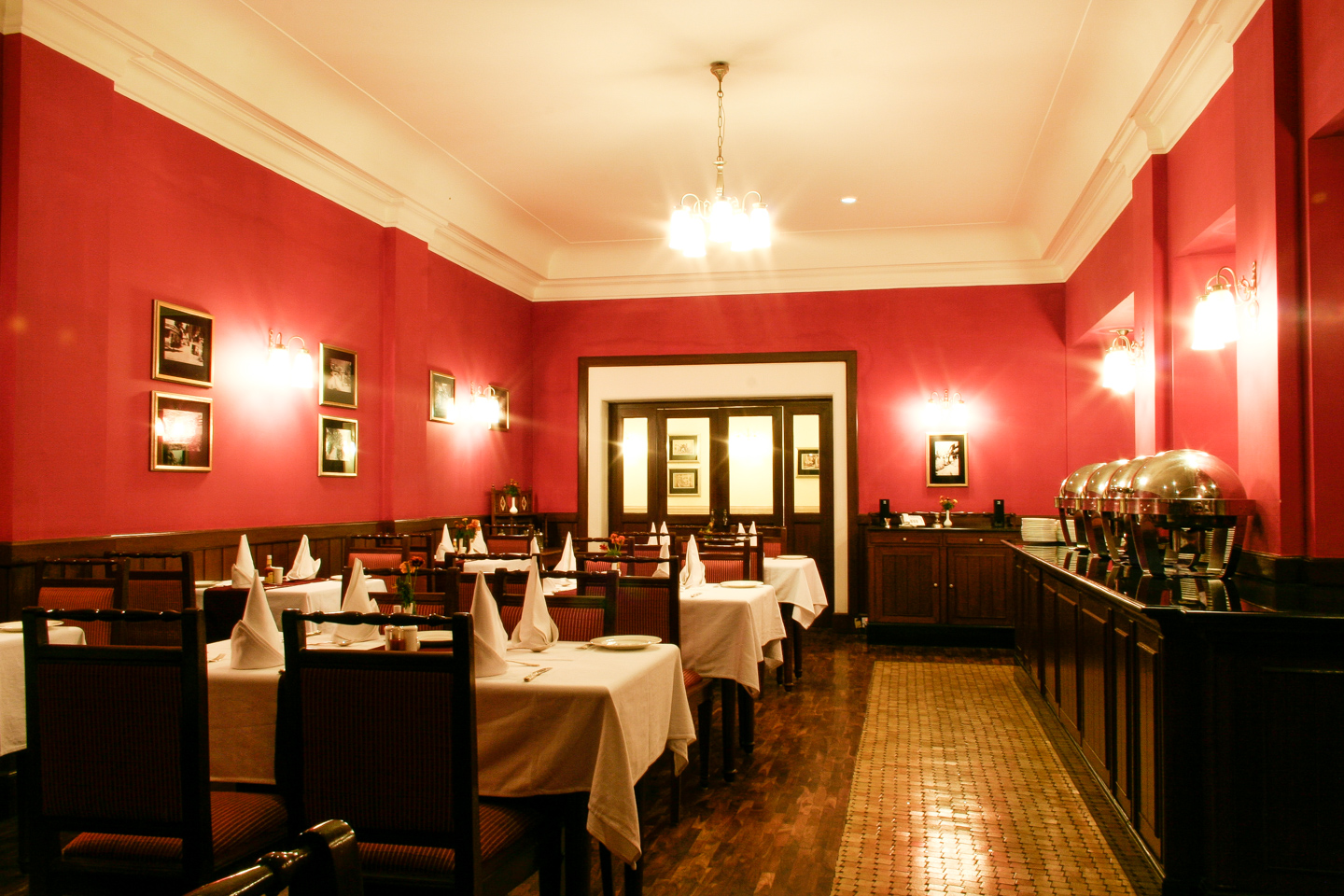 The dining room has wood panelling and deep red walls. The floor is parquet with period tiles.