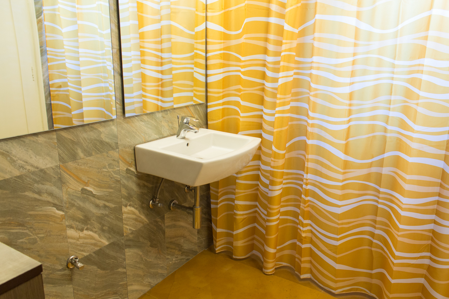 The guest bathroom has provision for a washing machine. The bathing area is behind the shower curtain.